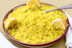 Shallow red-rimmed bowl with Saffron & Lemon Brown Basmati Rice garnished with 3 lemon wedges