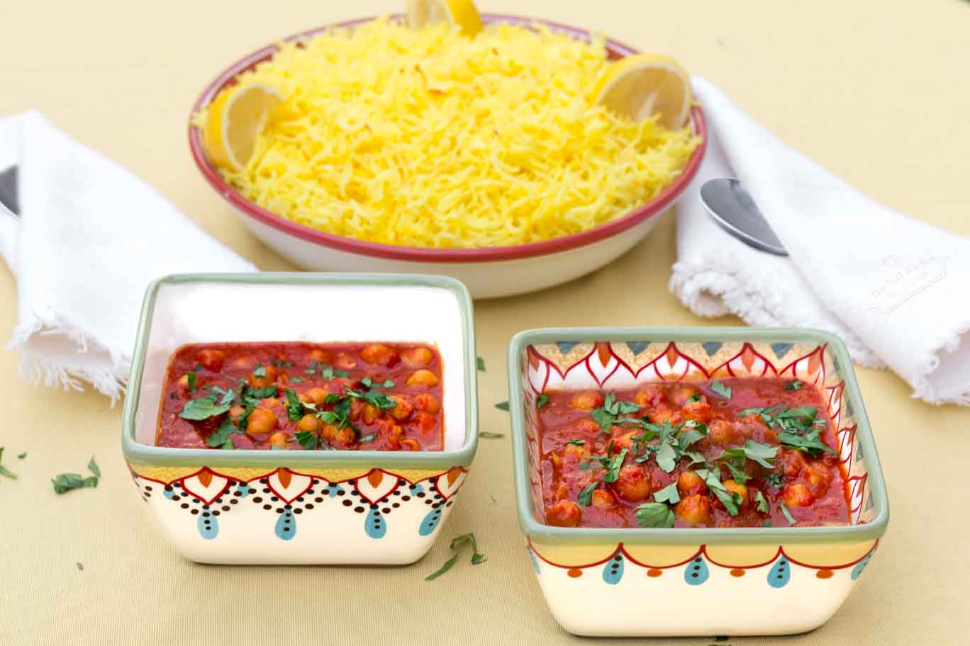 Two hand-painted bowls of Moroccan Inspired Warm-spiced Chickpeas with a bowl of Saffron & Lemon Infused Rice behind