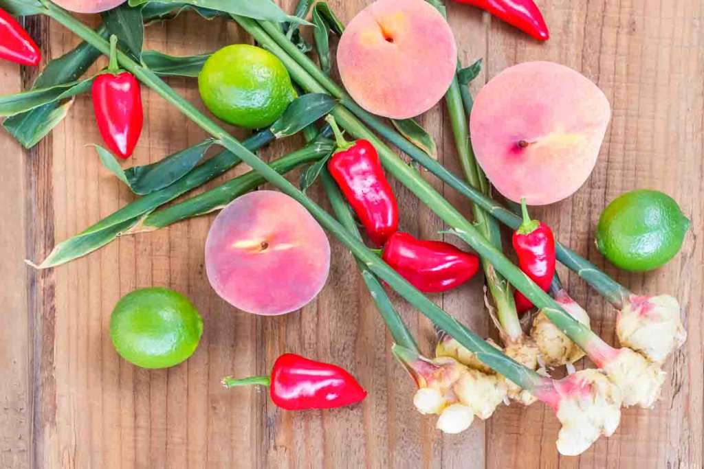 Wood board with Peach-ginger Dressing ingredients: young fresh ginger, red Fresno peppers, limes and peaches.