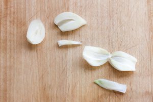 Garlic cloves on acutting board, cut lengthwise and showing the germ remove