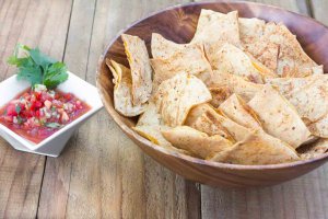 Wood bowl filled with Light & Crispy Oil-free Tortilla Chips and a ceramic dish with Garden Salsa Fresca