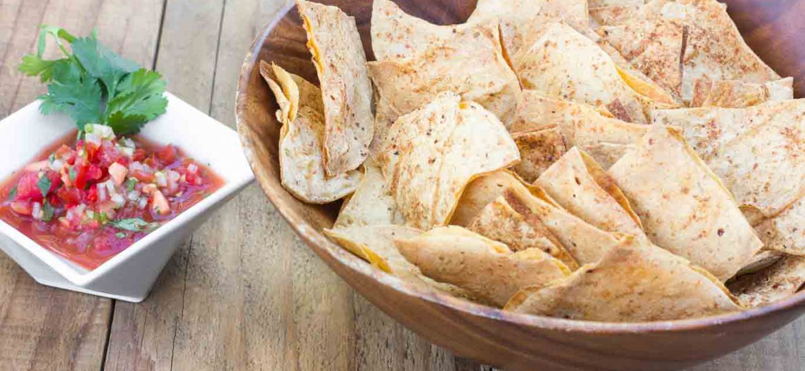 Wood bowl filled with Light & Crispy Oil-free Tortilla Chips and a ceramic dish with Garden Salsa Fresca