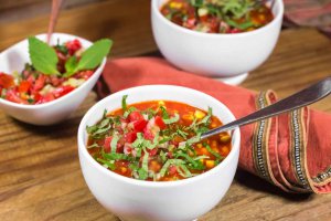 White round bowl with Oil-free vegan red pepper, chickpea and corn soup topped with homemade garden salsa fresca