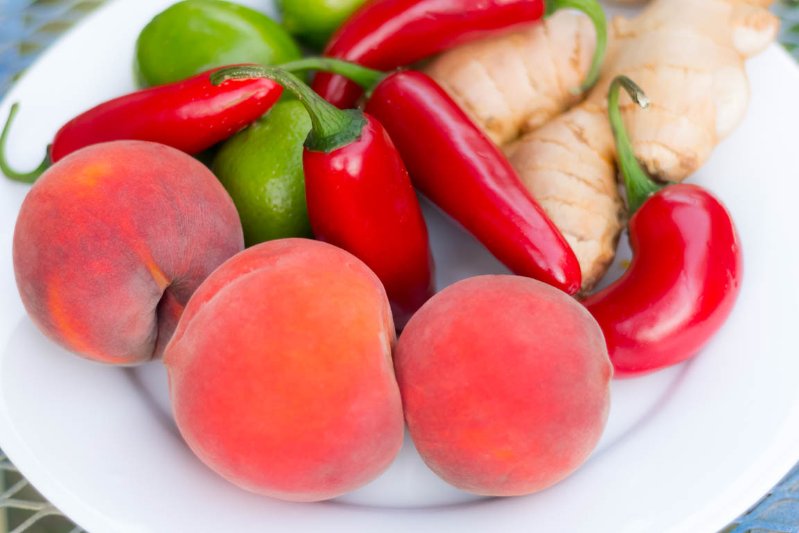 Peaches, red Jalapeno peppers, limes and ginger on a white plate