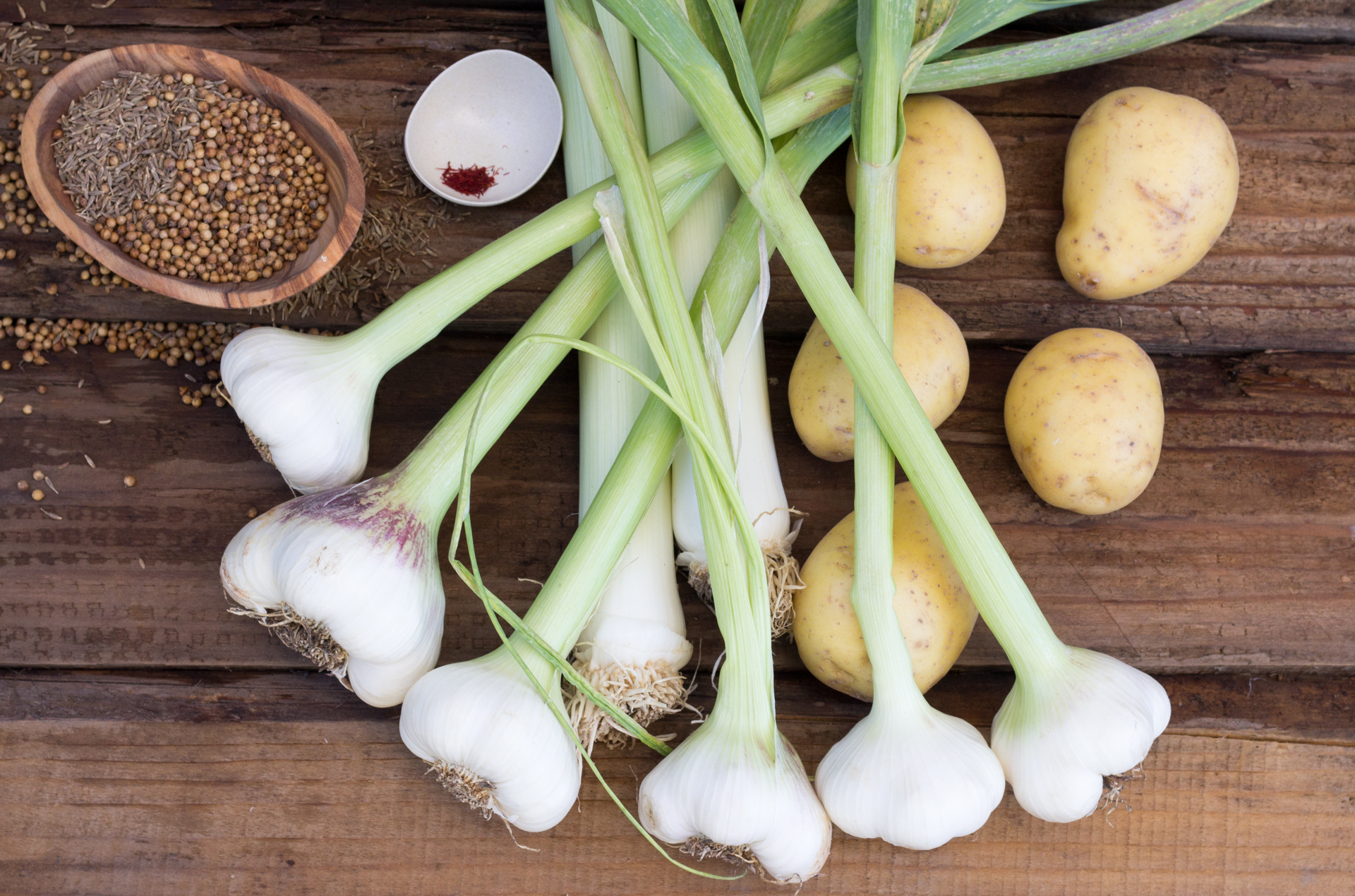 Springtime Fresh Garlic Soup Ingredients: fresh spring garlic, green garlic, Yukon Gold potatoes, saffron, cumin, coriander on a board