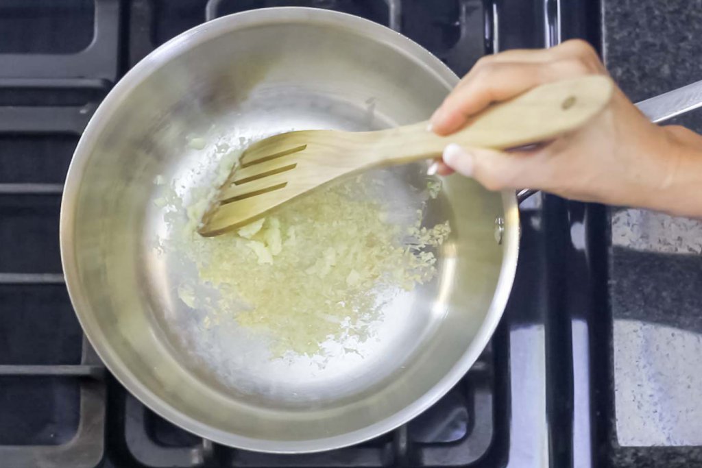 Making a layer of grated garlic on tha pan surface with an olivewood flat spatula