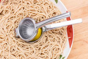 Stainless Steel Lemon Squeezer Squeezing lemon juice with a Stainless Steel Lemon Squeezer over a bowl of pasta.