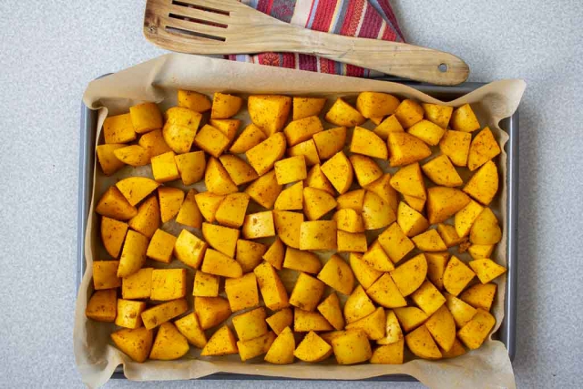 Baking sheet with spiced potatoes in a single layer ready for roasting