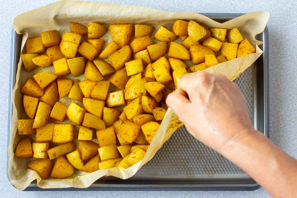 Lifting the parchment paper corner will help release the potatoes