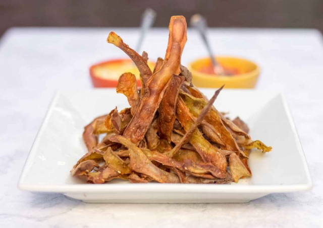 A white square plate with SOS free spiced potato skin crispy chips and two dips in small bowls