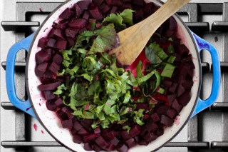 Beet greens and stalks added to the braiser pan with the beets