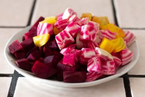 Mixed raw diced beets, Chioggia, Detroit red and Golden beets, on a round white plate