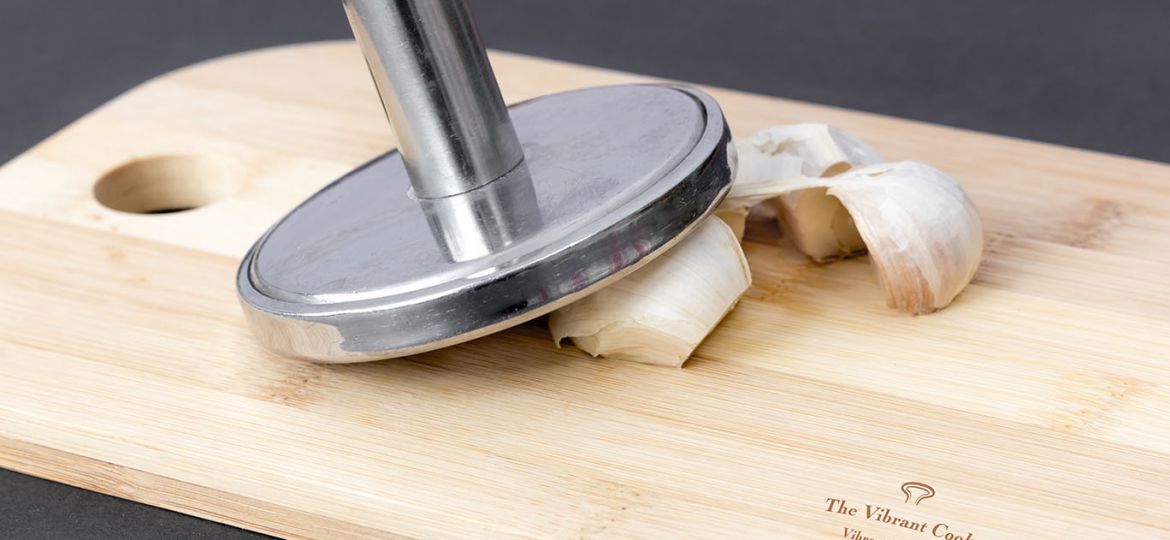 Garlic cloves on a cutting board. Tap the garlic cloves to remove the outer paper skin